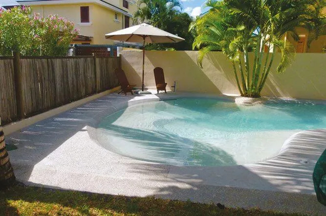 Private beach pool with sandy shoreline and lush garden backdrop